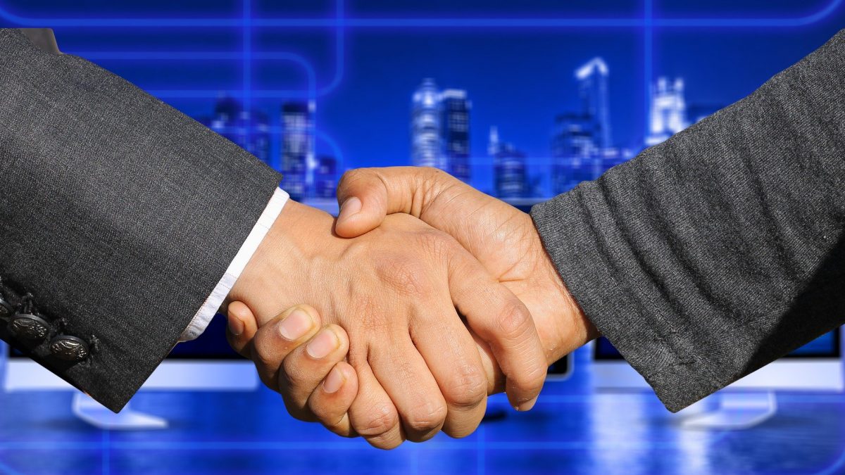 Car Dealership key management - Image of two business men shaking hands in front of a blue cityscape background